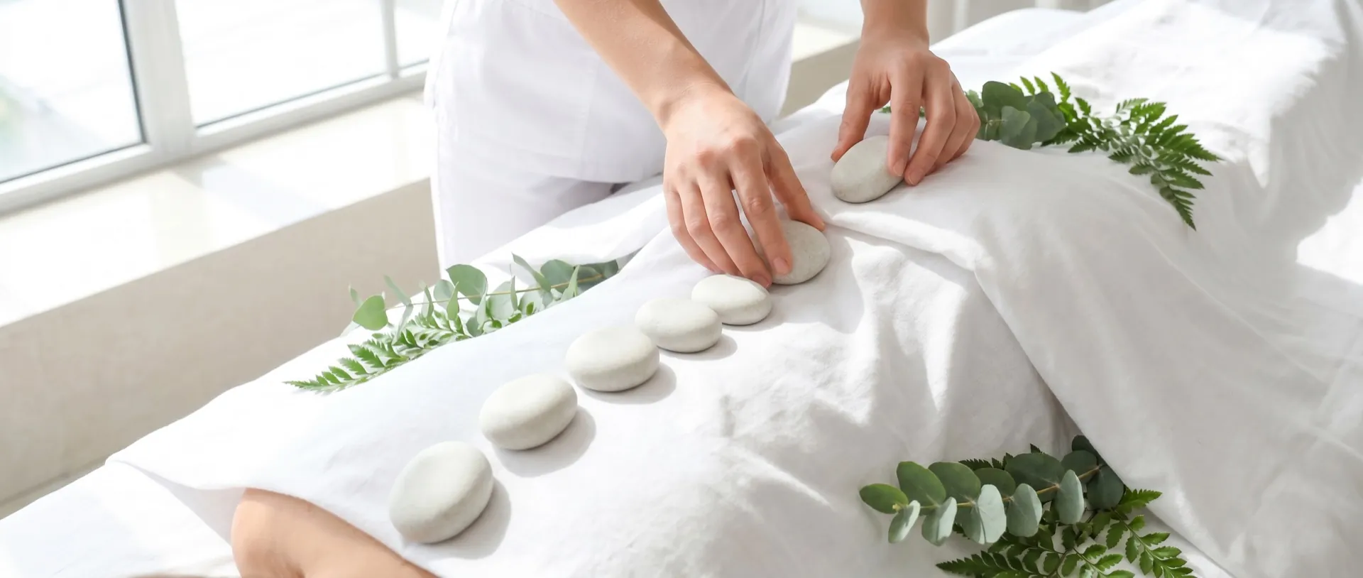Therapist placing warm, smooth stones along a client's back during a hot stone massage
